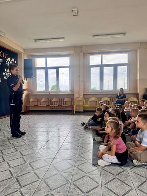 Policjantka w szkole, w tle dzieci.