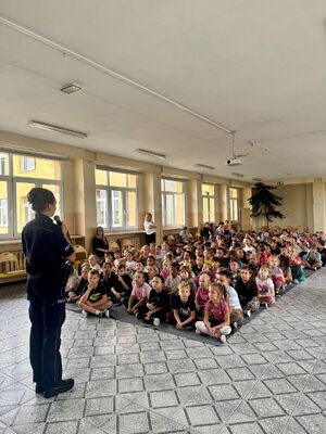Policjantka w szkole, w tle dzieci.