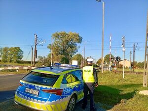 Policjanci, w tle przejazd kolejowy.