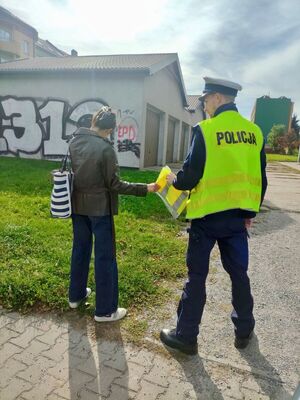 Policjanci rozdający kamizelki odblaskowe.