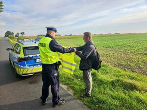 Policjanci rozdający kamizelki odblaskowe.