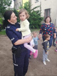 policjantka podczas prelekcji z dziećmi w przedszkolu, wzięła na ręce jedną z dziewczynek.