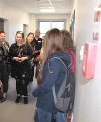 Dzielnicowy oprowadza uczniów liceum po pomieszczeniach dla osób zatrzymanych w KPP w Poddębicach.