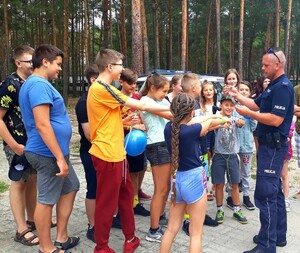 Dzielnicowy prezentuje młodzieży wyposażenie służbowe tj. kajdanki.